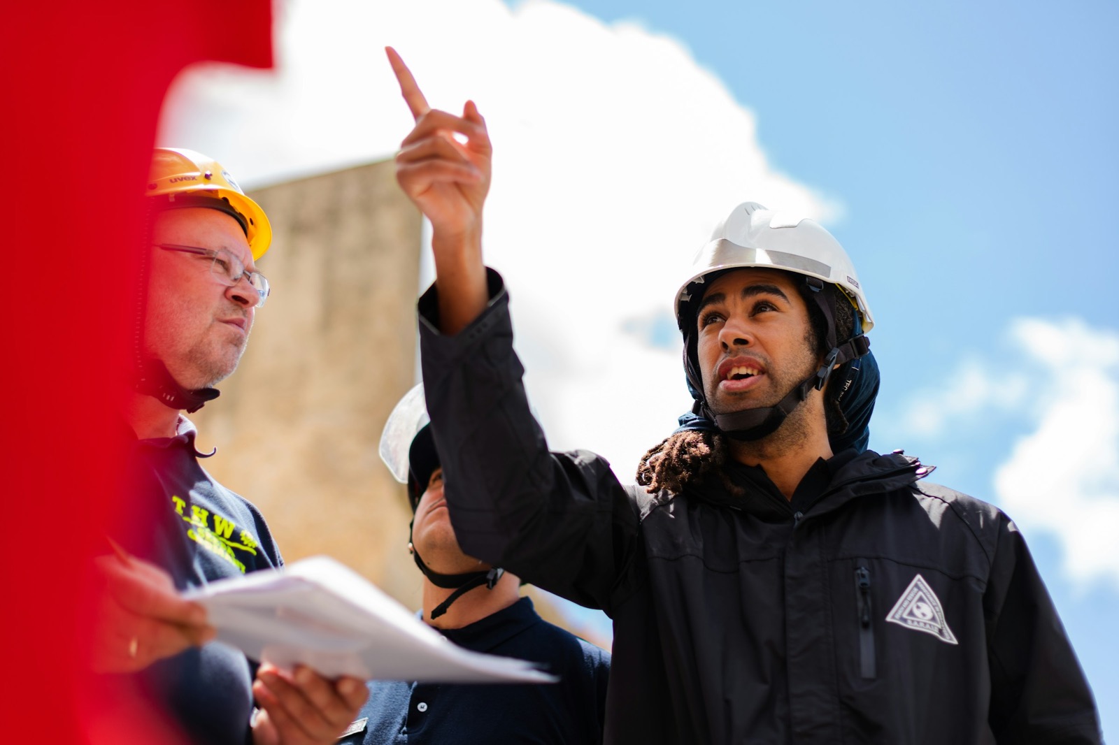 Profesionales con casco revisando documentos en obra